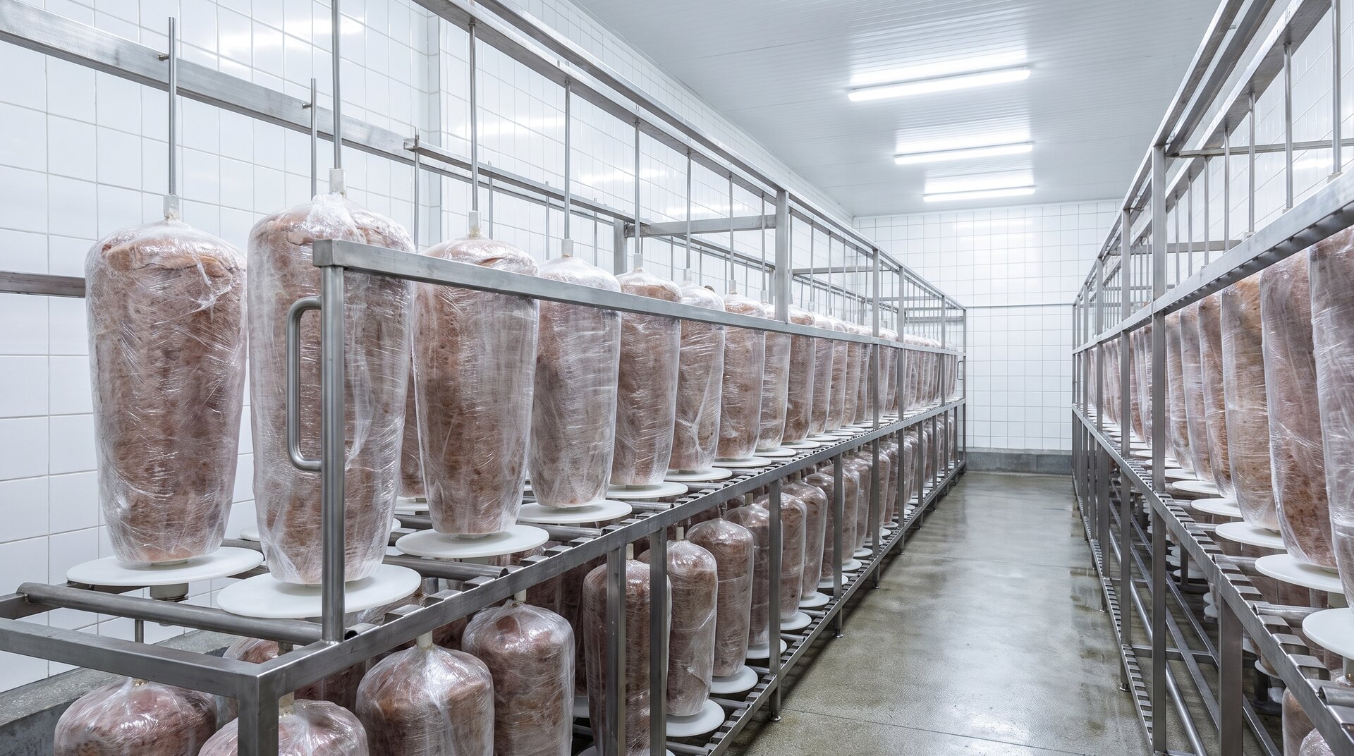 Zafoliowane tuby mięsa kebab na stelażach w zakładzie produkcyjnym
